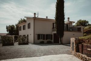 une grande maison blanche avec un arbre en face dans l'établissement La Pianaccia, à Manciano