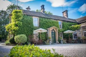 una casa cubierta de hiedra con sillas y sombrillas delante en Rafters at Riverside House Hotel, en Bakewell