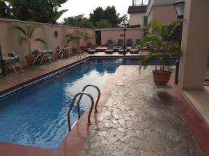 een zwembad met stoelen en tafels in een gebouw bij Room in Apartment - Best Western Plus-presidential Suite in Ibadan