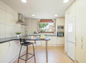 a kitchen with white cabinets and a table with a stool at Apart-rent Casa al canal Llobregat 0106 in Empuriabrava