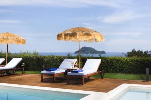 two chairs and umbrellas next to a swimming pool at Diomani Maison in Lithakia