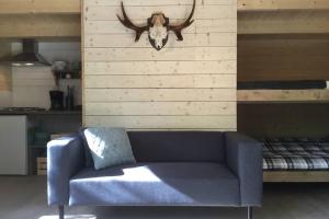 a blue couch with a bull head on a wall at Cozy Lodge in Värmland Sweden in Filipstad