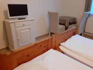 a room with two beds and a desk with a television at Pension Horvath jun. in Guntramsdorf