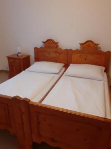 two wooden beds with white sheets in a room at Pension Horvath jun. in Guntramsdorf