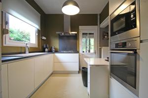 cocina con armarios blancos y ventana grande en - Charmante & chaleureuse maison -, en Waterloo