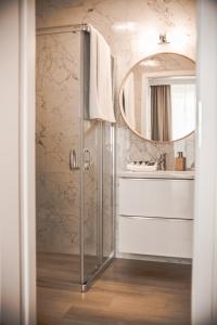 La salle de bains est pourvue d'une douche, d'un lavabo et d'un miroir. dans l'établissement Oaza w Centrum, à Białystok