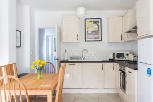 cocina con armarios blancos y mesa de madera en Bluebell Cottage Mumbles - Sea Views, en Mumbles