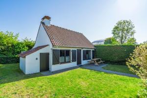 a small white cottage with a picnic table in a yard at Cottage 213 in Sunparks Oostduinkerke with free parking and garden in Koksijde