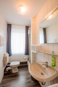 La salle de bains est pourvue de toilettes blanches et d'un lavabo. dans l'établissement Hotel Schiffer, à Bensersiel