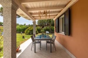 eine Terrasse mit einem Tisch und Stühlen unter einer Pergola in der Unterkunft Villa Zen - On the Beach in Costa Rei