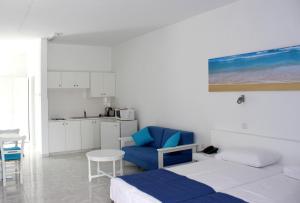 a bedroom with a bed and a blue chair and a kitchen at Flokkas Hotel Apartments in Protaras