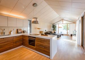 a kitchen with wooden cabinets and a living room at Reelinki Seafront Villa Amando in Pori