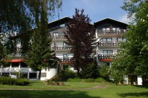 een groot wit gebouw met bomen ervoor bij Hotel Rhönhof in Oberleichtersbach