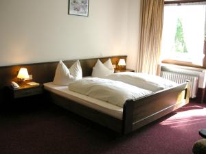 ein Schlafzimmer mit einem Bett mit weißen Laken und Kissen in der Unterkunft Hotel Rhönhof in Oberleichtersbach