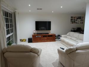 a living room with two couches and a flat screen tv at Golden Retreat in Golden Grove