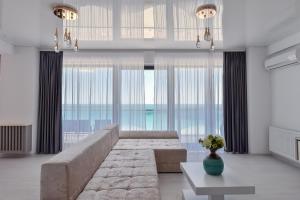 a living room with a large couch and large windows at AZIMUTH Hotel by Building Stefan - Hotel Building Stefan Resort I Sud in Mamaia Sat/Năvodari