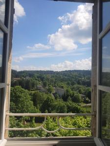 una ventana abierta con vistas al bosque en Gite La Coustourelle - Appartement T4 en coeur de village, en Le Chambon-sur-Lignon