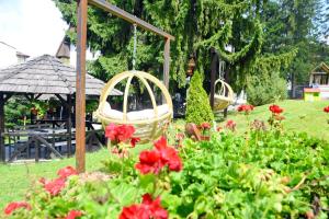 um jardim com flores vermelhas e um baloiço em Elexus Boutique em Predeal