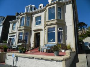 una casa bianca con una panchina davanti di Sunnyside House a Rothesay