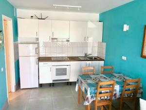 eine Küche mit weißen Schränken sowie einem Tisch und Stühlen in der Unterkunft Apartamento Los Lagos in Cotillo
