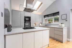 a kitchen with white cabinets and a skylight at Rothiemay House - Donnini Deluxe in Prestwick +7 photos