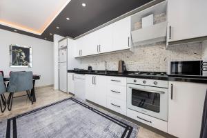 eine Küche mit weißen Schränken und einem Esstisch in der Unterkunft Çınar 1-2 - 2 Bedroom with jacuzzi in Kalkan in Kaş