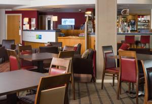 ein Restaurant mit Tischen und Stühlen und eine Bar in der Unterkunft Holiday Inn Express London Chingford by IHG in London