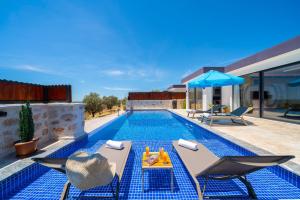 einen Pool mit zwei Stühlen und einem Tisch neben einem Haus in der Unterkunft Çınar 1-2 - 2 Bedroom with jacuzzi in Kalkan in Kaş