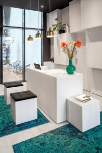 a white lobby with a vase of flowers on a counter at AMANO HOME Apartments in Berlin