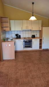 a kitchen with white cabinets and a tile floor at Schönermarker Pferdeparadies in Niederlandin