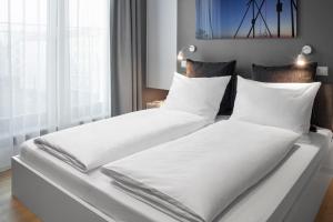 - 2 lits dans une chambre avec des draps et des oreillers blancs dans l'établissement AMANO HOME Apartments, à Berlin