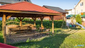 a wooden gazebo with a table and chairs in a yard at Pokoje Salsa in Dąbki