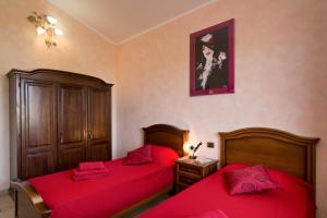 2 letti in una camera con lenzuola rosse di Villa Limone a Gonnesa
