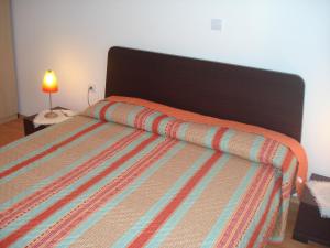 1 dormitorio con 1 cama con edredón de rayas naranjas en Apartments Buzleta II, en Fažana