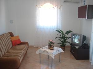 sala de estar con sofá, mesa y TV en Apartments Buzleta II, en Fažana