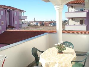 a table on a balcony with a vase of flowers at Apartments Buzleta II in Fažana