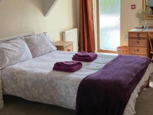 a bed with two purple towels on top of it at Station House, Dartmoor and Coast located, Village centre Hotel in South Brent