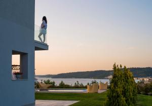 a woman standing on the balcony of a house at Soleado Luxury Villas in Skala Fourkas