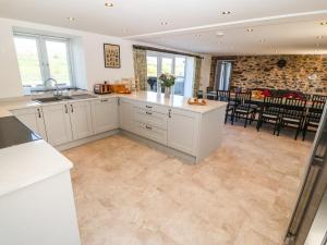a kitchen with white cabinets and a stone wall at Bwthyn Y Bugail Shepherd's Cottage in Oswestry