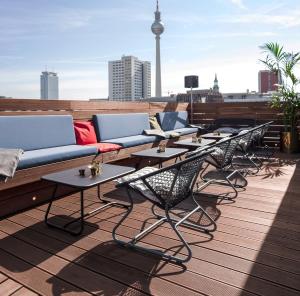 une rangée de tables et de canapés sur un toit dans l'établissement Hotel ZOE by AMANO, à Berlin