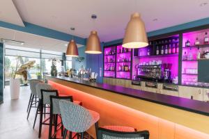 a bar in a restaurant with purple lighting at Aparthotel Adagio Bâle Mulhouse Aeroport in Blotzheim