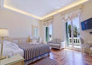a bedroom with a bed and a chair and windows at Hotel De Paris Sanremo in Sanremo
