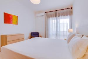 Un dormitorio con una gran cama blanca y una ventana en AL - Apartamento Infante Sagres en Quarteira