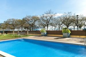 a blue swimming pool with a fence and trees at the beach milenium in Roses