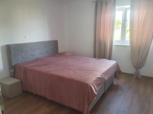 a bedroom with a bed with a red bedspread and a window at Muring Apartments in Tribunj