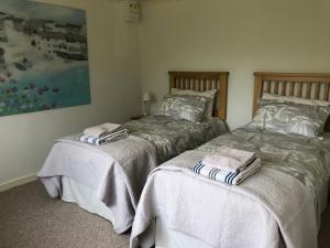 2 nebeneinander sitzende Betten in einem Schlafzimmer in der Unterkunft Sycamore Bungalow in Perranwell