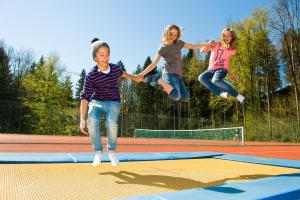 three girls jumping in the air on a trampoline at MONDI Resort und Chalet Oberstaufen in Oberstaufen