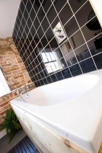 a white bath tub in a bathroom with black tiles at Dog and Whistle Pub in Hertford