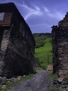 an old stone building with a car in a field at Raul Lushnu Darbaz in Mestia