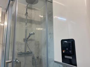 ducha con puerta de cristal y dispensador de jabón en La Fleur Marine Classé 3 étoiles - Accès direct mer Cabourg, en Cabourg